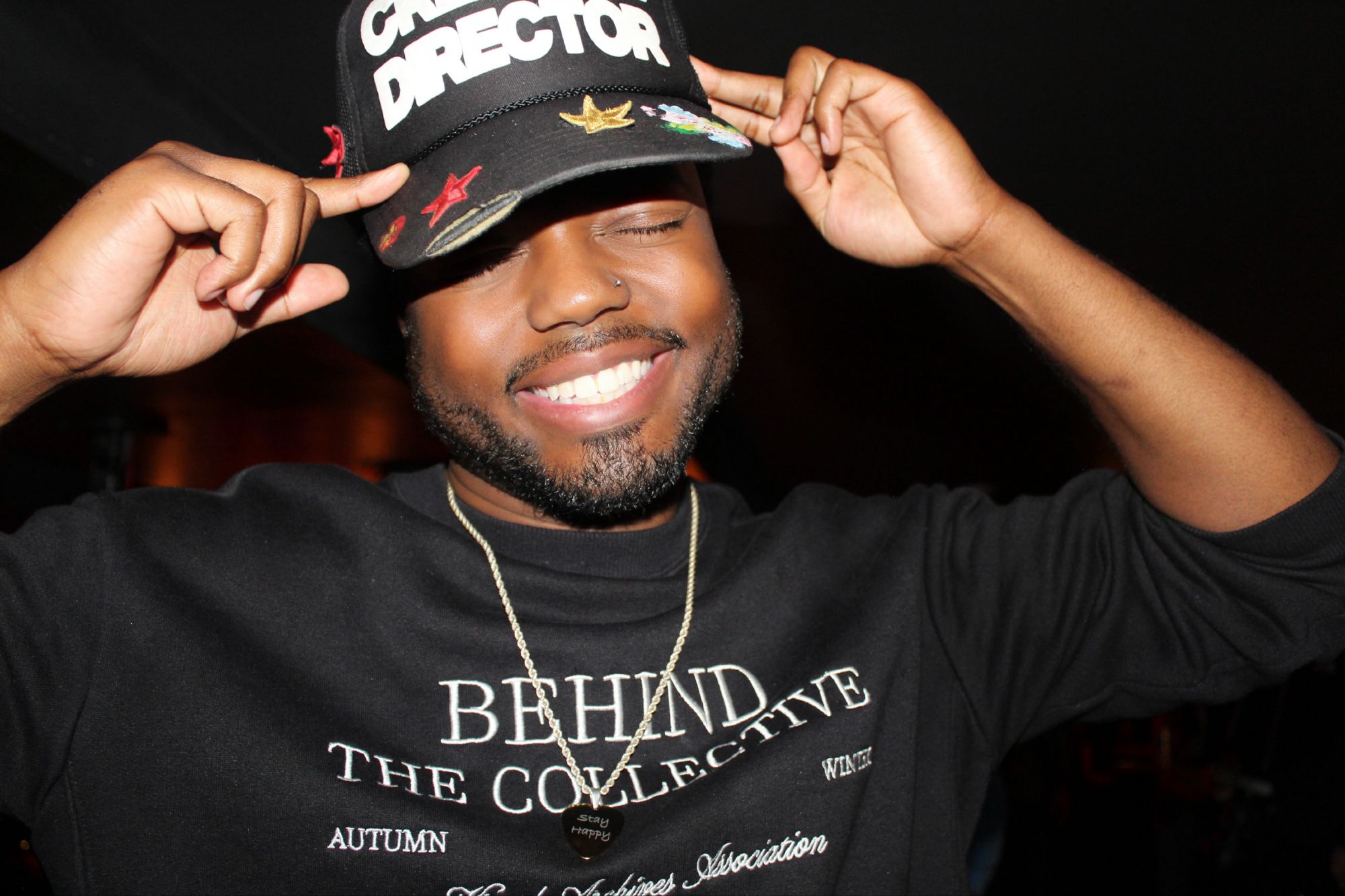 Justis smiling and tipping his Creative Director hat